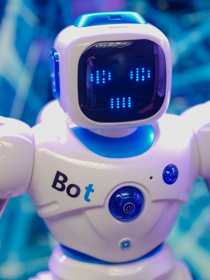 White humanoid robot toy with illuminated face display representing modern technology.